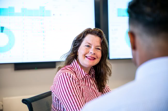 Dame smiler foran en skjerm